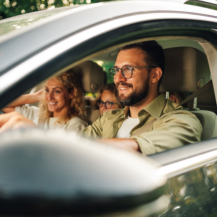 family in their car smiling on a drive